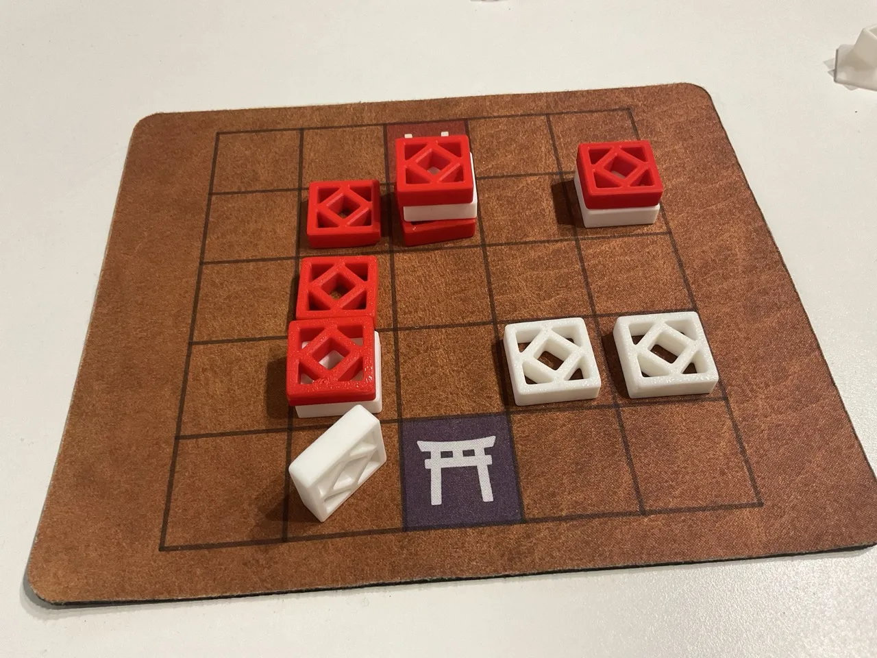 A game of Tak played with 3D printed red and white tiles on a 5 by 5 grid.