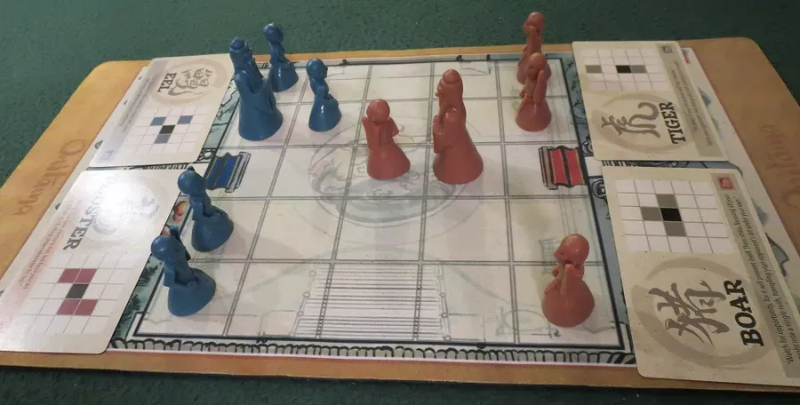A game of Onitama with blue and red minifigure pawns.
