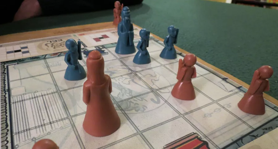 A closeup of Onitama board with red and blue pieces on the board