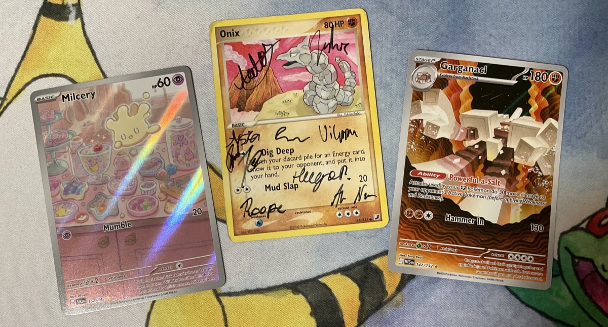 Pokémon cards: a full-art Milcery, a full-art Garganacl and in the middle, an Onix card with signatures all over it.