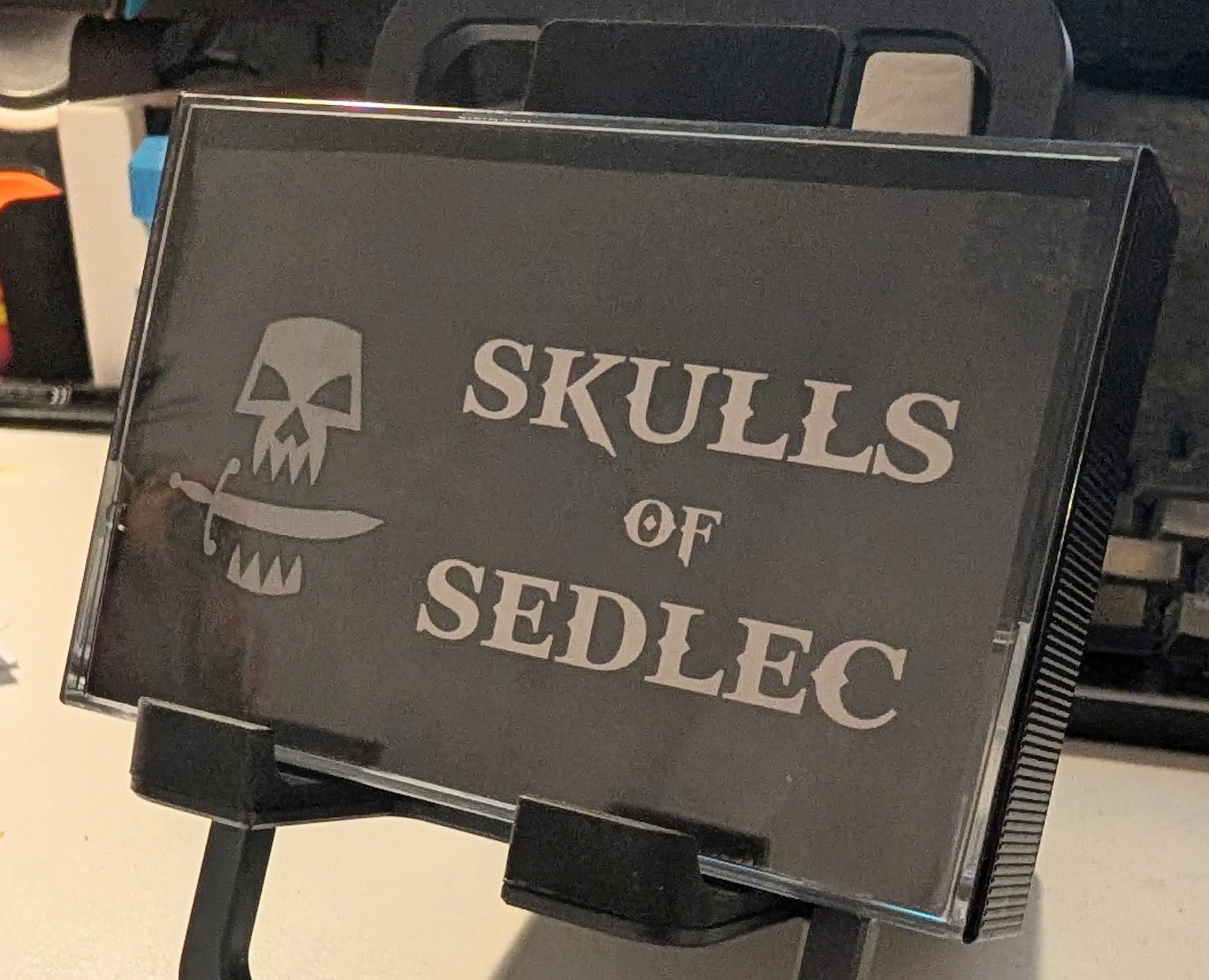 A closed C cassette case with Skulls of Sedlec written on the cover with an icon of skull with a sword in its mouth.