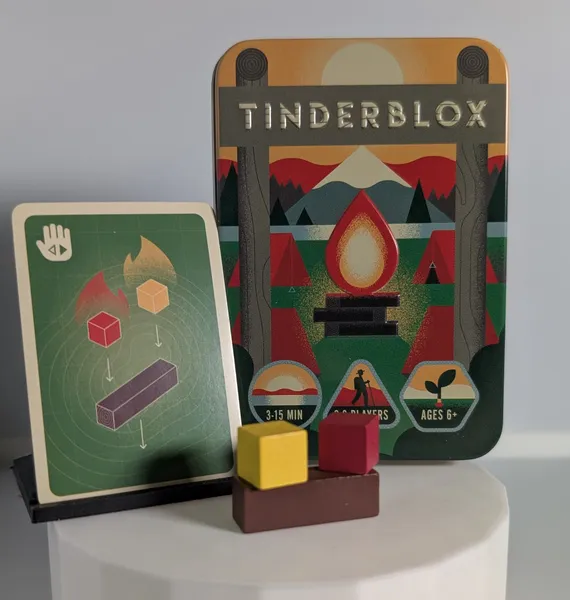 Tinderblox tin, a single card showing a task of placing a log and two fire cubes and a log and two fire cube components.