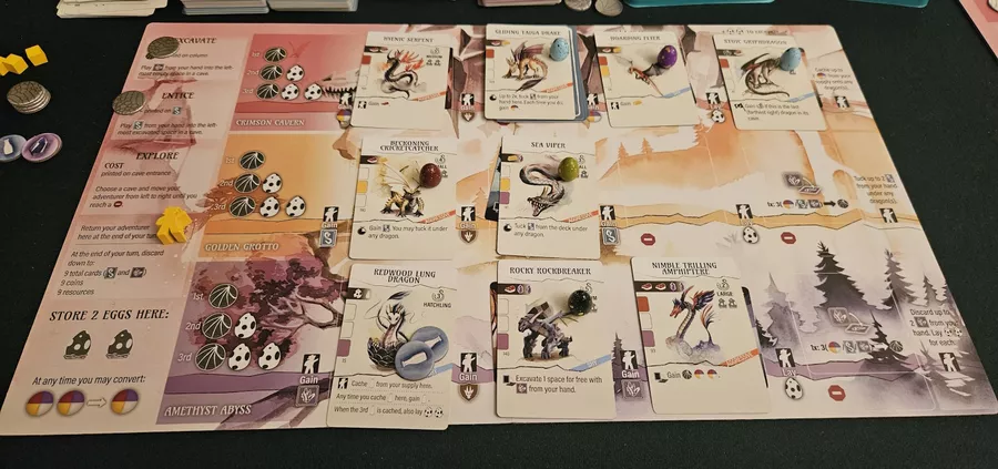 A late-game player mat in Wyrmspan with three rows of dragons, some with eggs and some with milk resources on them.